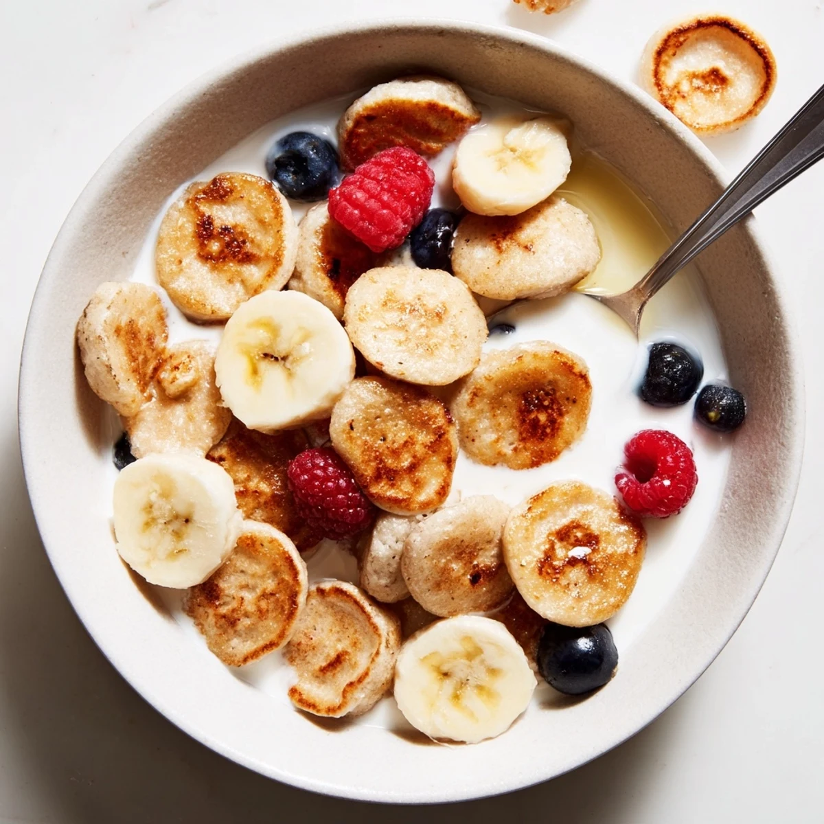 Mini Pancake Cereal overflowing with fresh berries and drizzled with rich maple syrup.  
