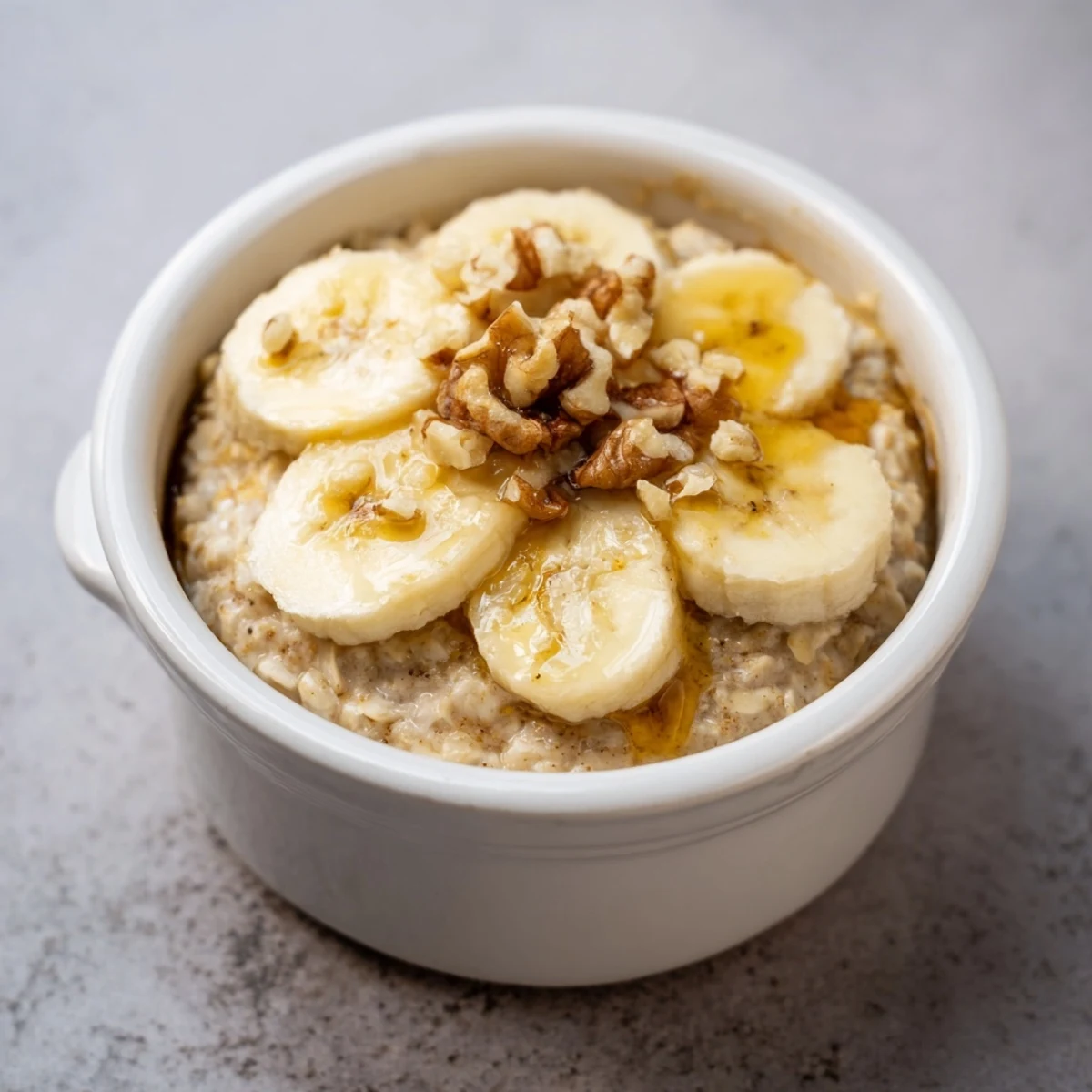 Golden-brown Baked Oats Ramekins with Banana, topped with sliced bananas and a drizzle of sweet honey.