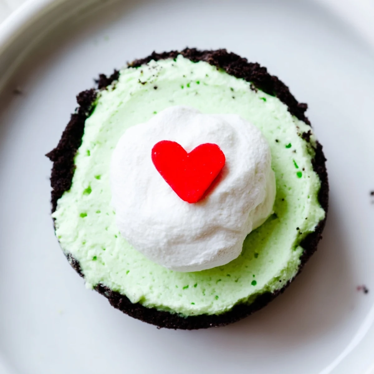 Festive Grinch Mini Cheesecakes, bright green and topped with whipped cream, are a delicious holiday dessert.