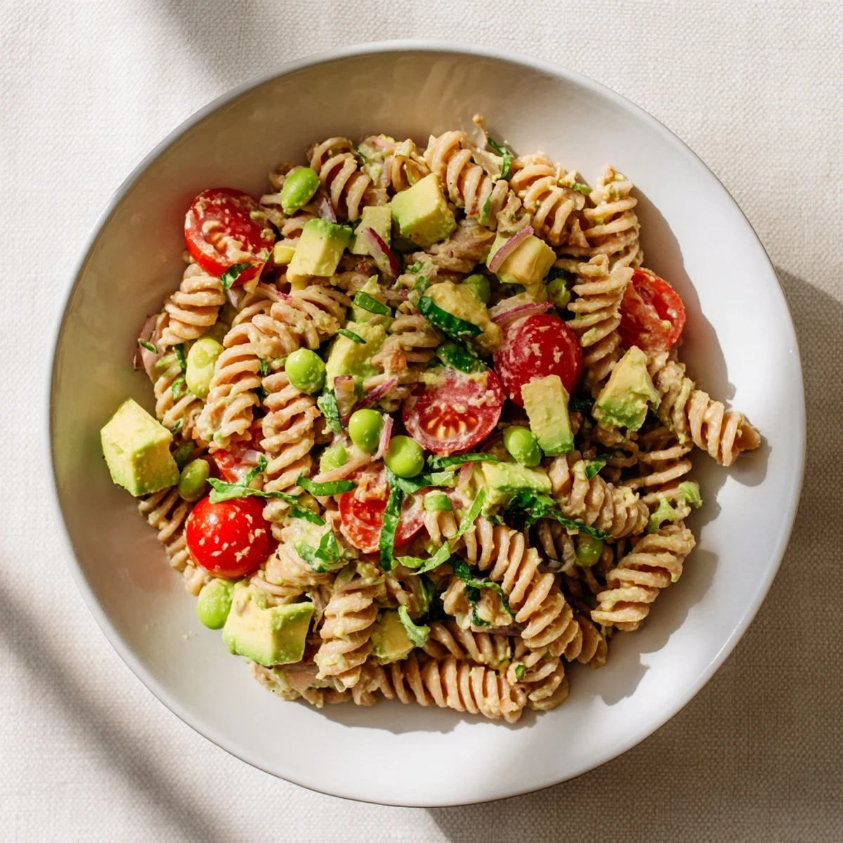 A bowl of fresh Holiday Glow Green Goddess Protein Pasta Salad with glistening dressing, ready to eat.