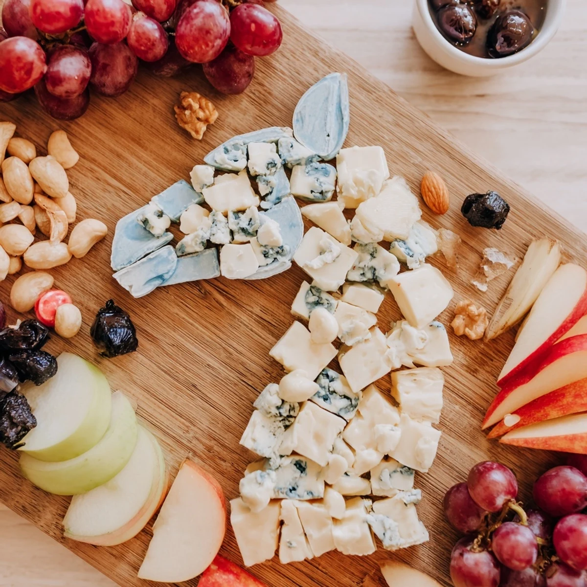 A stunning horse-shaped grazing board overflowing with cheeses, meats, fruits, and crackers for a party.