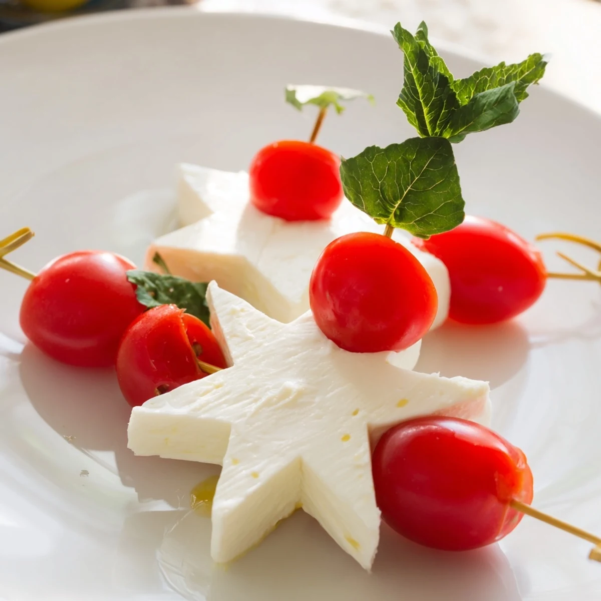 Star-shaped Caprese skewers: bright red tomatoes, creamy mozzarella stars, and fragrant basil leaves.