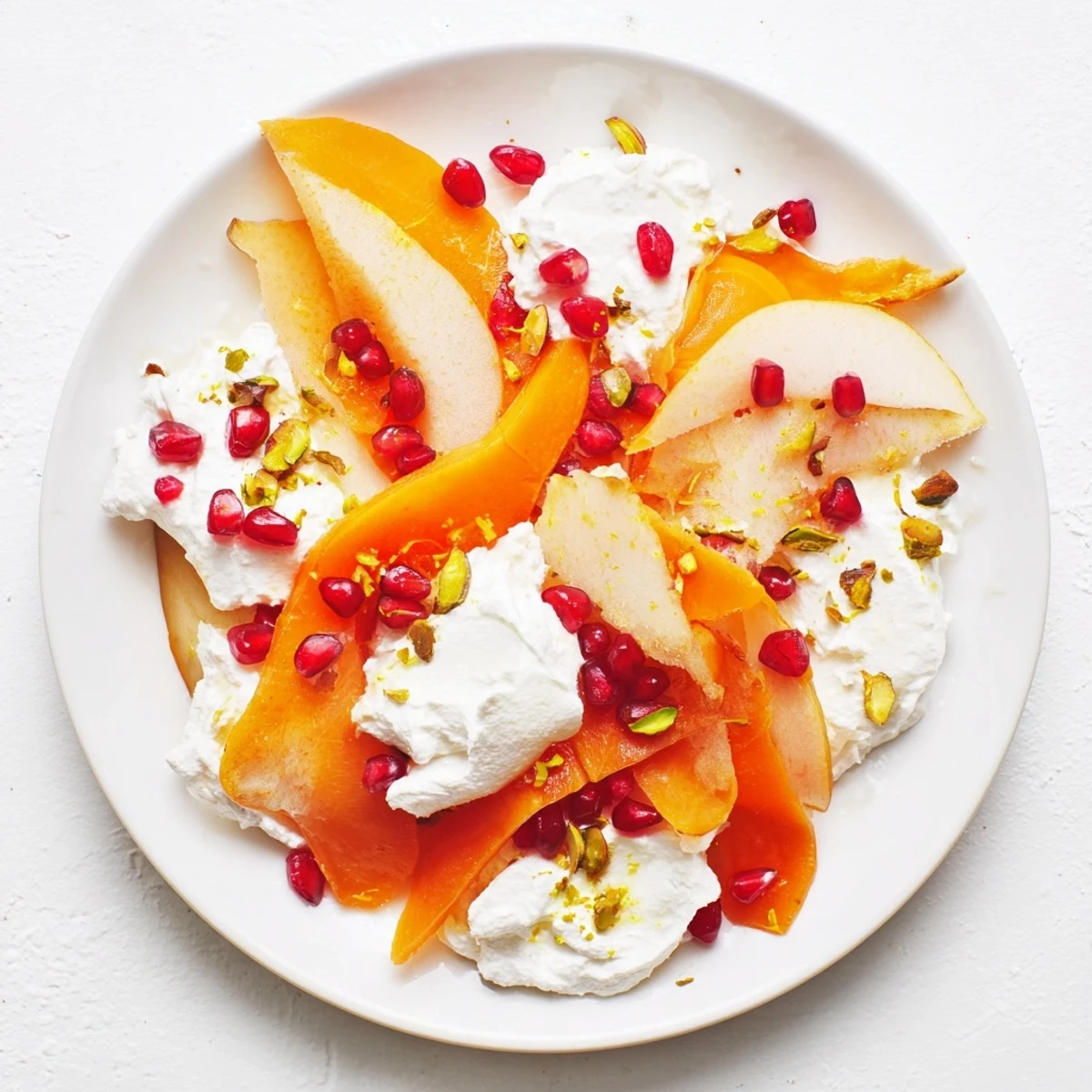 Fresh persimmon and pear snowscape, a gluten-free dessert garnished with jewel-toned pomegranate seeds.