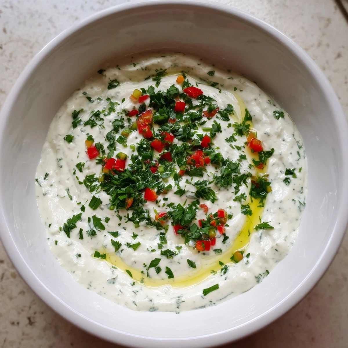 Vibrant red and yellow bell pepper strips surround a bowl of creamy Greek yogurt dip, ready to eat.