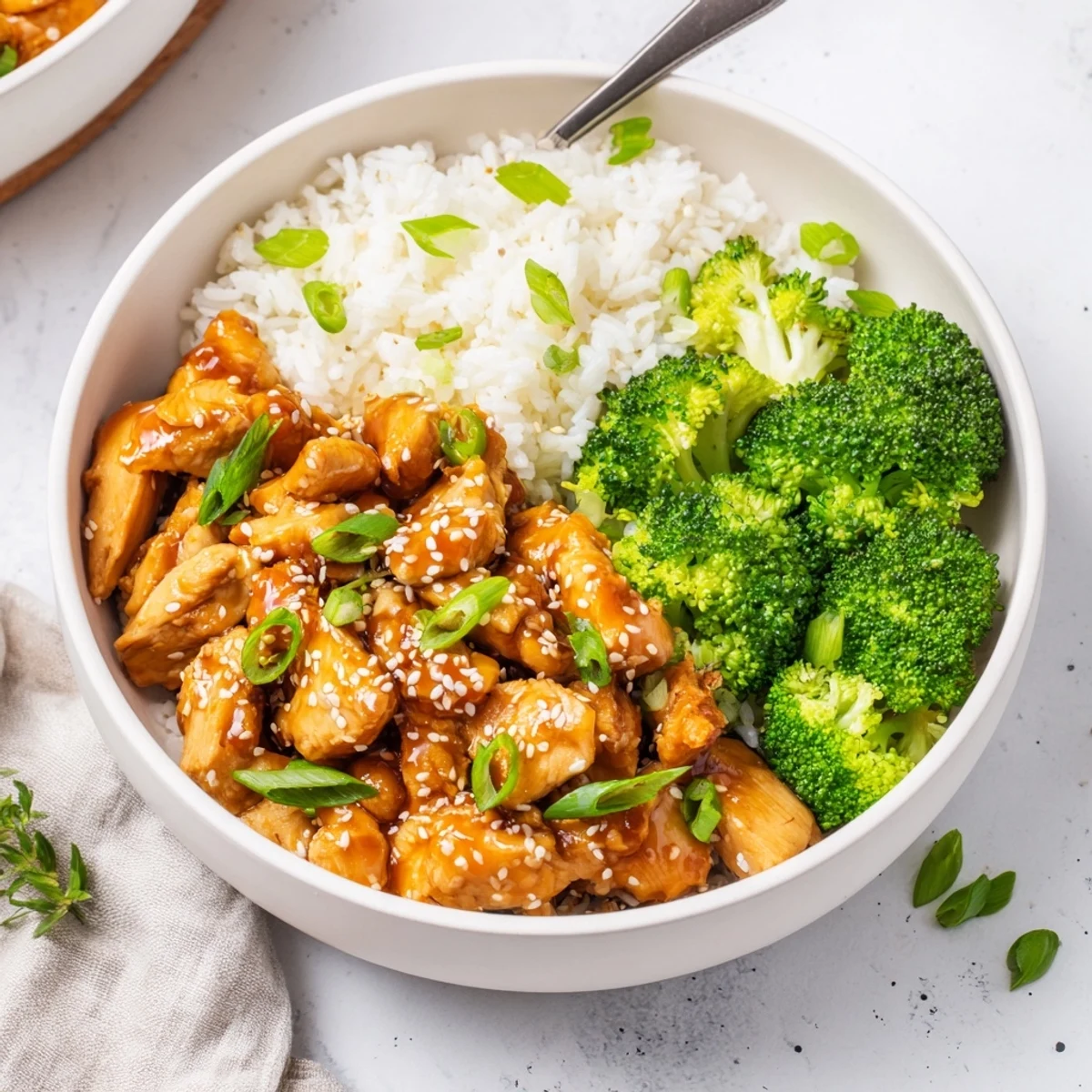 Glazed sweet chili chicken and steamed broccoli bowl, served over fluffy white rice with green onions and sesame seeds.