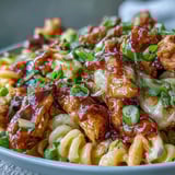 Creamy cheddar macaroni and glazed chicken in a Sticky Honey BBQ Chicken Pasta Skillet, ready to serve.