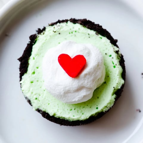 Festive Grinch Mini Cheesecakes, bright green and topped with whipped cream, are a delicious holiday dessert.