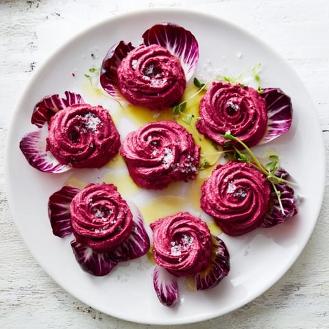 Vibrant beet hummus roses, part of The Velvet Rose appetizer, served on crisp red radicchio leaves.