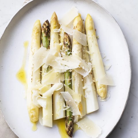 Elegant The Silver Birch starter: tender white asparagus, creamy cheese, and black truffle shaving's aromatic essence.
