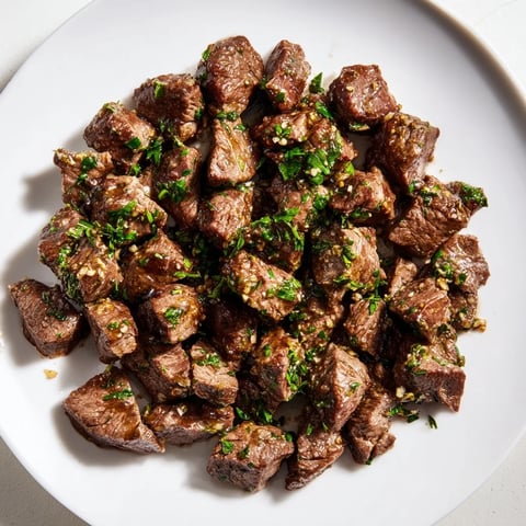 Golden-brown air-fryer garlic-butter steak bites, glistening in a savory sauce, ready to serve and enjoy.