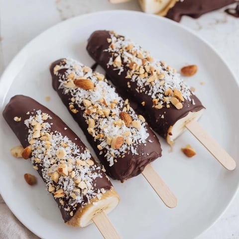 Frozen Banana Chocolate Pops: Peanut butter and chocolate-covered frozen banana popsicles with crunchy peanut toppings.