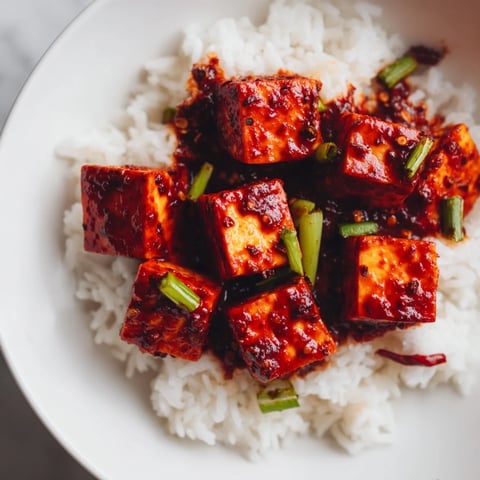Steaming jasmine rice topped with a vibrant and spicy Chinese Mapo Tofu dish.