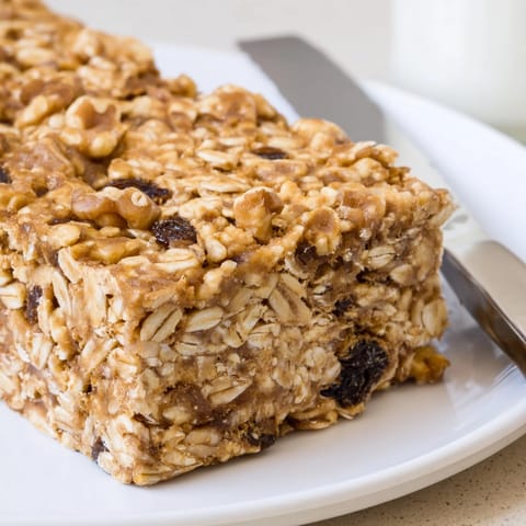 Warm, oven-fresh homemade Peanut Butter Cinnamon Raisin Bars cooling on a parchment-lined baking pan.