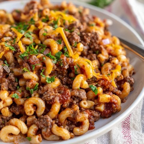 Comforting Grandma’s Goulash, topped with melted cheese and fresh parsley for garnish.  