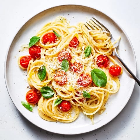 A close-up view of steaming Lazy-Girl Pasta, tossed with fresh basil and Parmesan cheese for a delightful meal.
