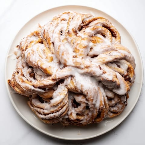 A close-up of a warm, frosted Giant Snowflake Sweet Roll, ready to be pulled apart.