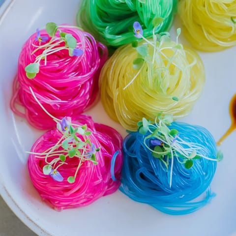 A refreshing shot of a bowl of neon noodle clouds, ready to be enjoyed with the dipping sauce.