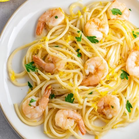 Close-up of a forkful of Lemon Garlic Shrimp Pasta, highlighting juicy shrimp and silky lemon garlic butter sauce coating the spaghetti.  