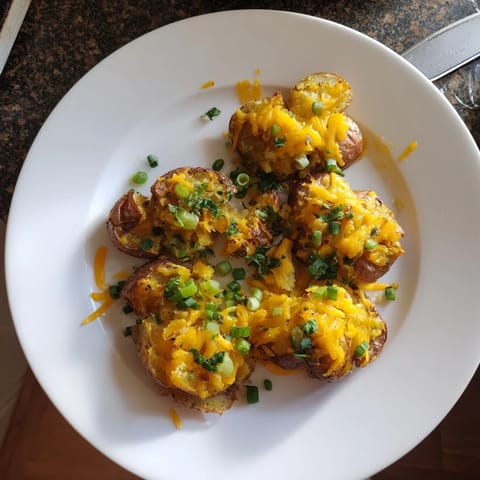 Crispy smashed green onion potato bombs topped with melted cheese and fresh herbs.