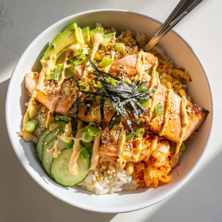 A colorful Crispy Salmon Rice Bowl with crispy garlic, fresh cucumbers, and sesame seeds.  