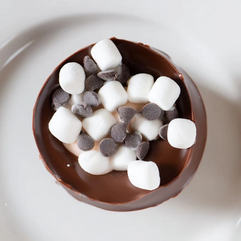 Fluffy marshmallows spilling from budget-friendly hot cocoa bomb cups, ready for a warm winter drink.