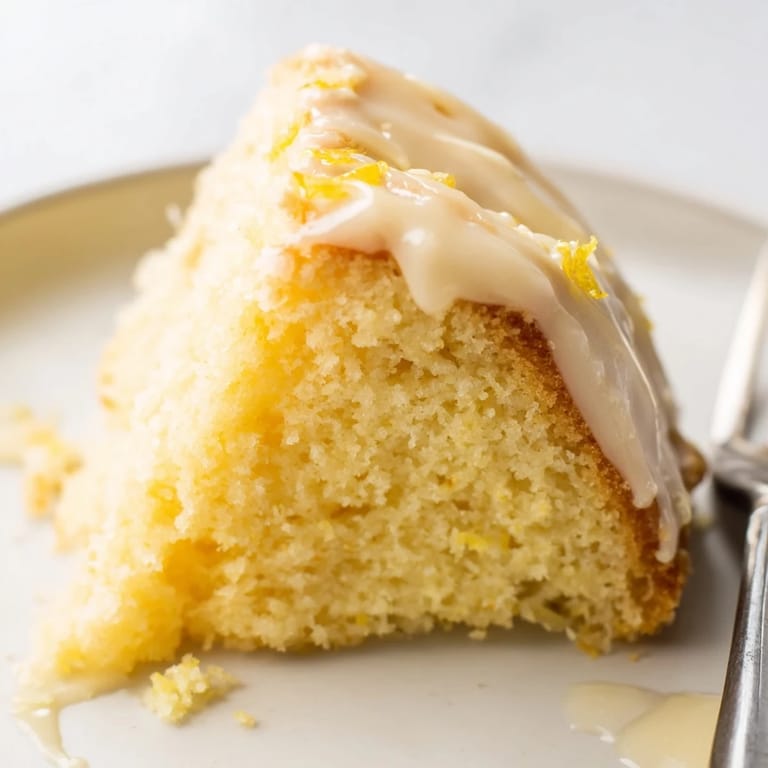 A close-up of a golden-brown Lemon Yogurt Cake, highlighting its moist texture and bright flavor.