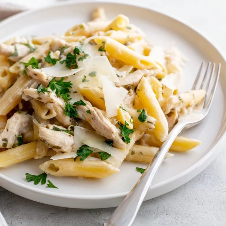 Roasted garlic chicken penne served in a warm bowl, paired with a crisp white wine and crusty bread.