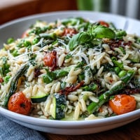 A colorful bowl of Spring Orzo Primavera with tender asparagus, zucchini, and snap peas tossed in parmesan and lemon zest.